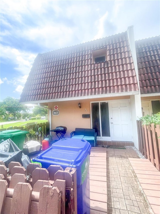 exterior space with stucco siding and a tile roof