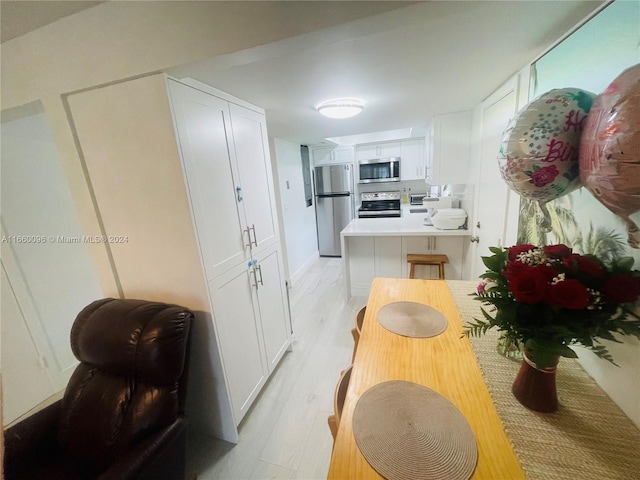 kitchen with white cabinets, light wood-type flooring, and stainless steel appliances