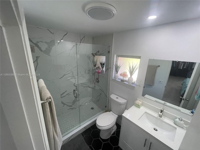 bathroom featuring tile patterned flooring, vanity, toilet, and a shower with shower door