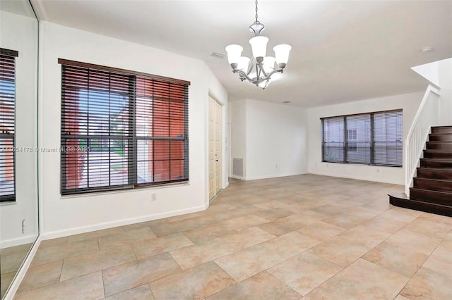 unfurnished living room with an inviting chandelier, baseboards, and stairway