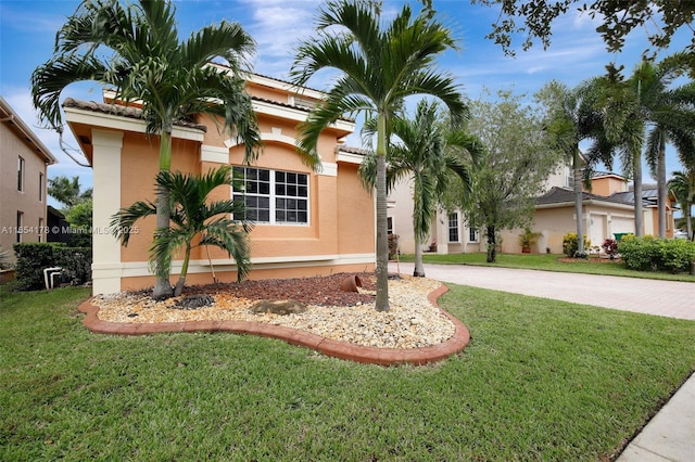 view of front of home featuring driveway, stucco siding, a front lawn, and a tile roof