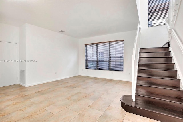 staircase featuring visible vents, baseboards, and plenty of natural light