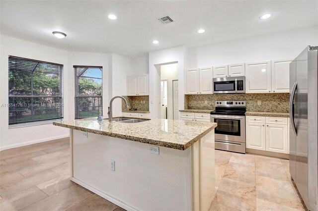 kitchen featuring white cabinets, sink, a kitchen island with sink, appliances with stainless steel finishes, and decorative backsplash