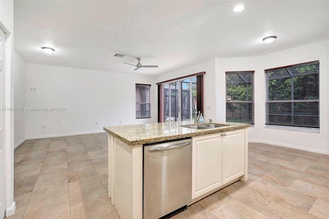 kitchen featuring ceiling fan, dishwasher, a center island with sink, and light stone counters