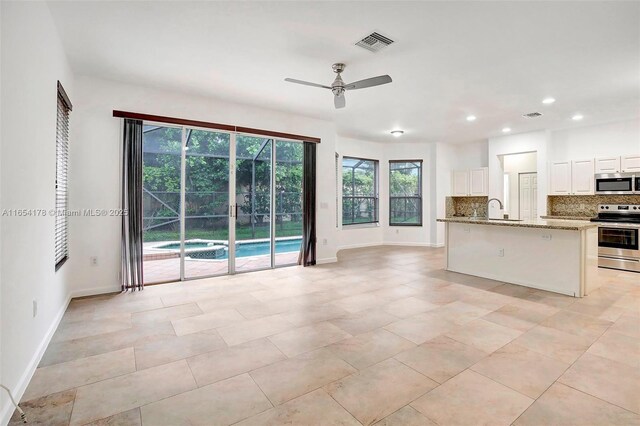 kitchen with ceiling fan, light stone countertops, appliances with stainless steel finishes, and plenty of natural light