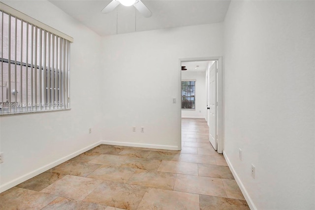 unfurnished room with ceiling fan and baseboards