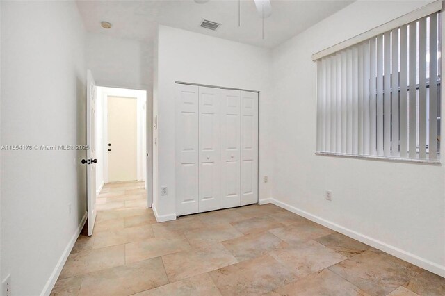 unfurnished bedroom with ceiling fan and a closet