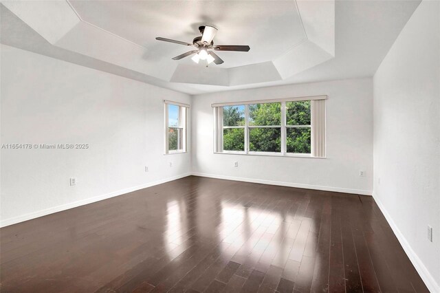 unfurnished room with a raised ceiling, dark hardwood / wood-style floors, and ceiling fan