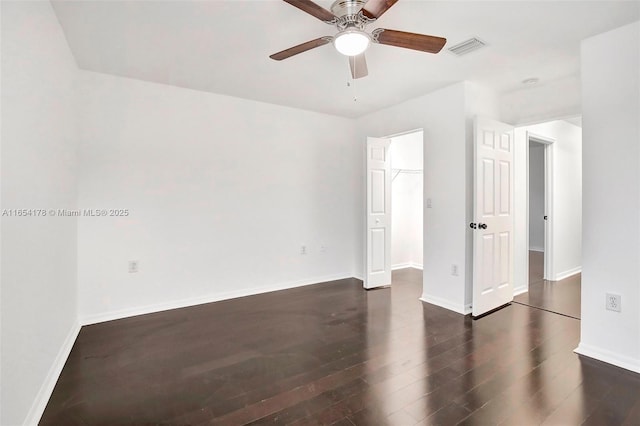 interior space featuring ceiling fan, visible vents, wood finished floors, a walk in closet, and baseboards