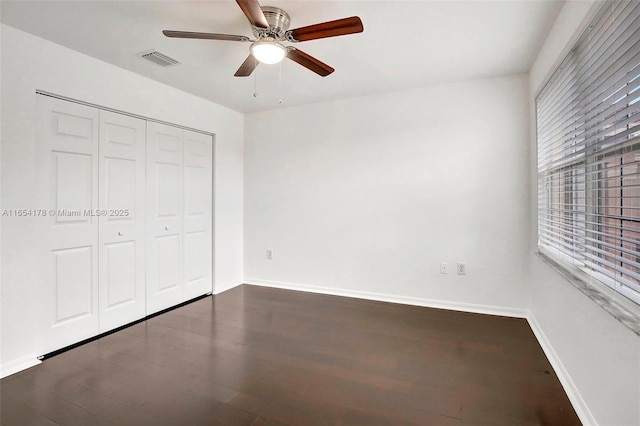 unfurnished bedroom featuring wood finished floors, baseboards, a closet, and visible vents