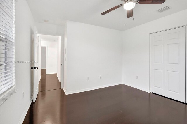 unfurnished bedroom featuring ceiling fan, a closet, and dark wood-type flooring