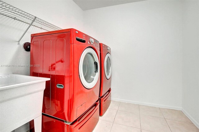 washroom with light tile patterned floors, washer and dryer, and sink