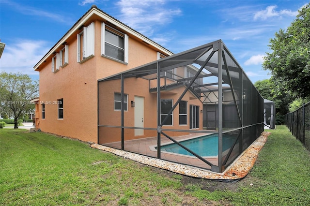 rear view of house featuring stucco siding, a patio area, a yard, glass enclosure, and fence
