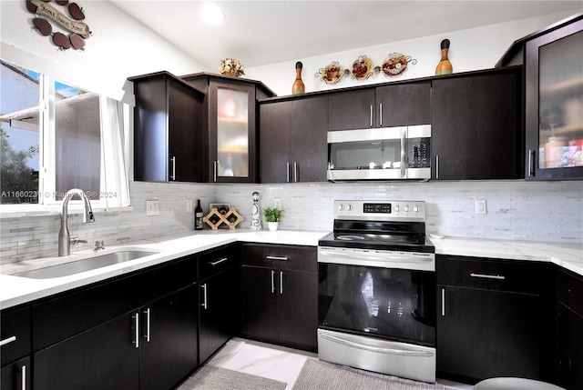 kitchen with appliances with stainless steel finishes, dark brown cabinets, decorative backsplash, and sink