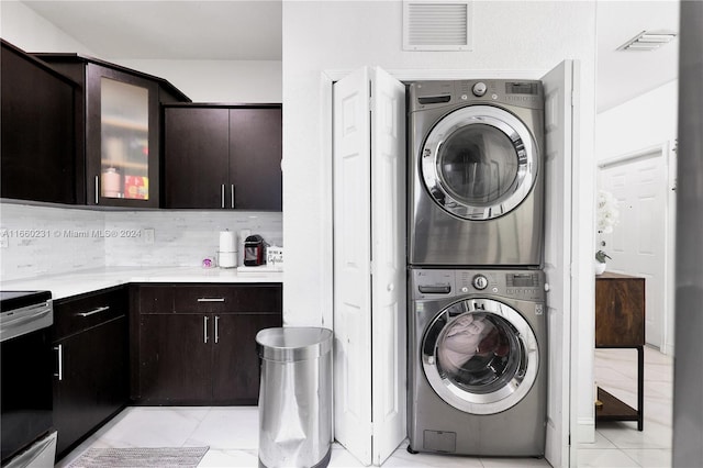 laundry room with stacked washer and clothes dryer and light tile patterned floors