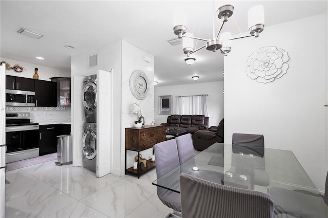 dining area featuring stacked washing maching and dryer and an inviting chandelier