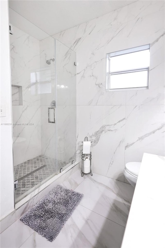 bathroom featuring a shower with door and toilet