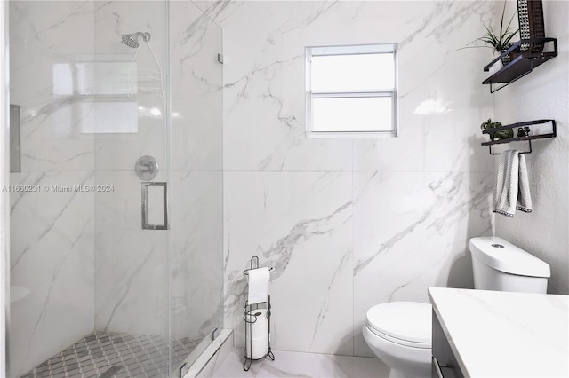 bathroom with tile walls, vanity, toilet, and a shower with shower door