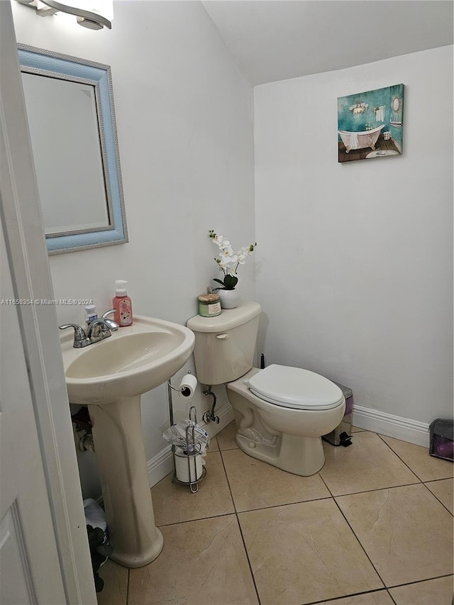 bathroom with toilet, sink, and tile patterned floors