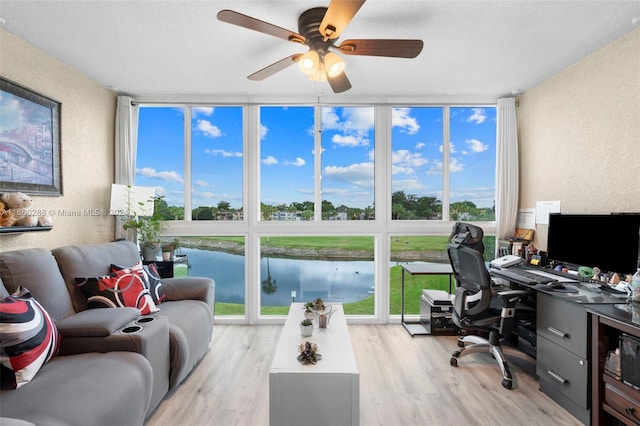 office space featuring floor to ceiling windows, light wood-type flooring, and a wealth of natural light