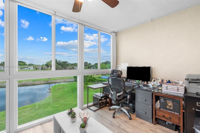 office with floor to ceiling windows, a water view, light hardwood / wood-style flooring, ceiling fan, and a textured ceiling