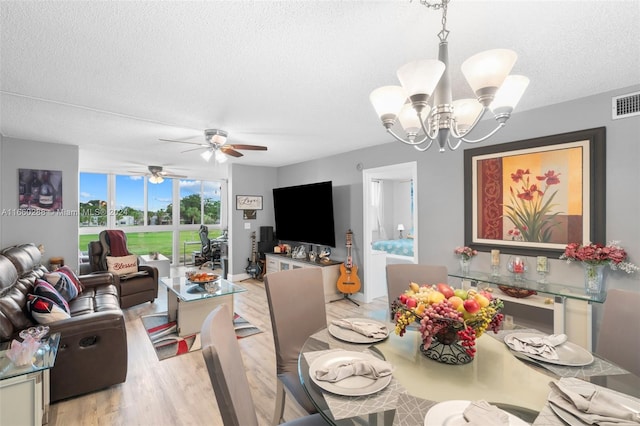 dining area featuring ceiling fan with notable chandelier, a textured ceiling, and light wood-type flooring