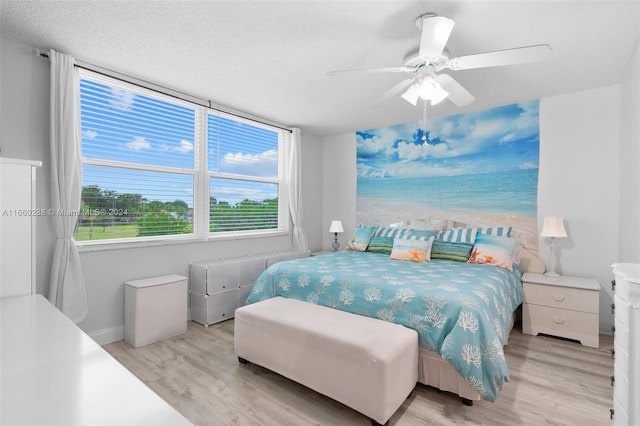 bedroom with ceiling fan, light hardwood / wood-style flooring, and a textured ceiling