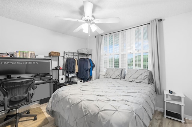 bedroom featuring ceiling fan, light hardwood / wood-style flooring, and a textured ceiling