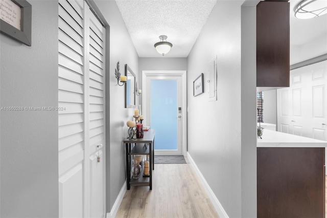 hallway with light wood-type flooring and a textured ceiling