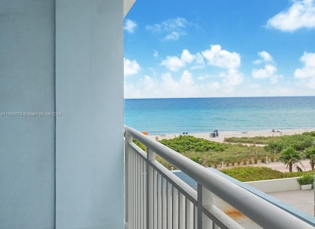 balcony with a water view and a view of the beach