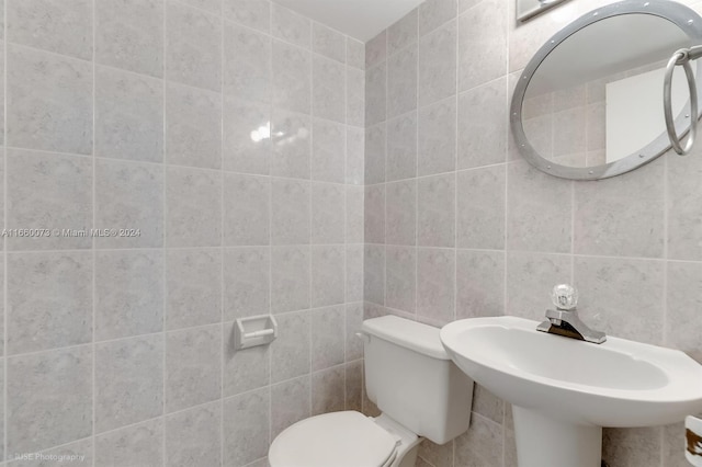 bathroom with tile walls, toilet, and sink