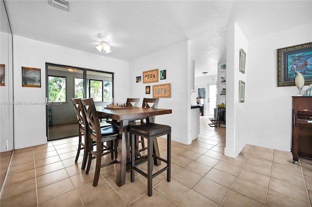 tiled dining area with ceiling fan and a textured ceiling