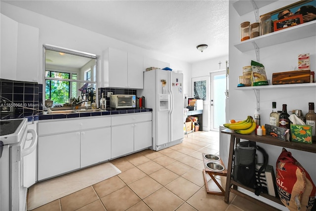 kitchen with backsplash, white appliances, sink, white cabinetry, and tile counters