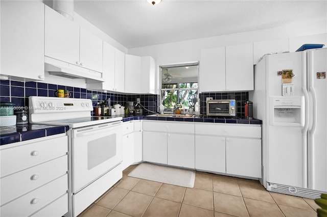 kitchen featuring white appliances, tile countertops, white cabinetry, and backsplash