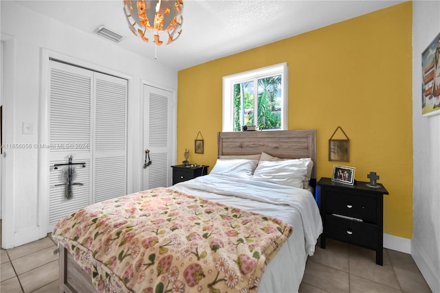 bedroom featuring light tile patterned floors and multiple closets