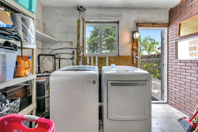 washroom featuring washer and dryer, brick wall, and water heater