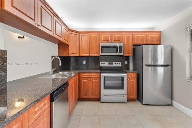 kitchen featuring light tile patterned flooring, sink, backsplash, appliances with stainless steel finishes, and dark stone countertops