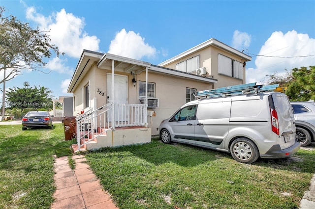 view of front of house with cooling unit and a front lawn