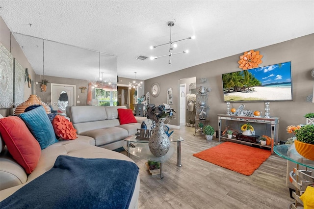 living room with a textured ceiling, light hardwood / wood-style flooring, and a chandelier