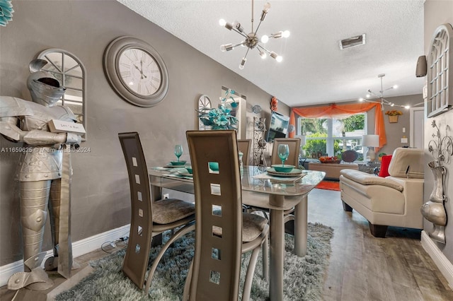 dining area with a textured ceiling, hardwood / wood-style floors, and a notable chandelier