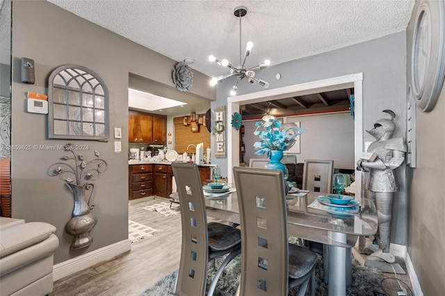 dining space featuring a textured ceiling, light hardwood / wood-style flooring, and a notable chandelier