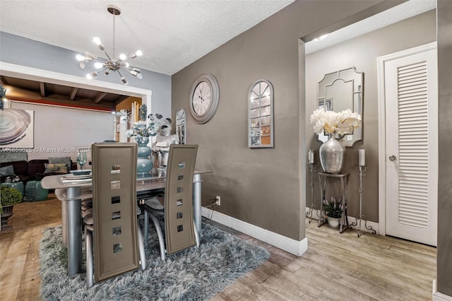 dining room featuring hardwood / wood-style flooring, a notable chandelier, and a textured ceiling