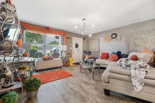 living room with wood-type flooring, an inviting chandelier, and a textured ceiling