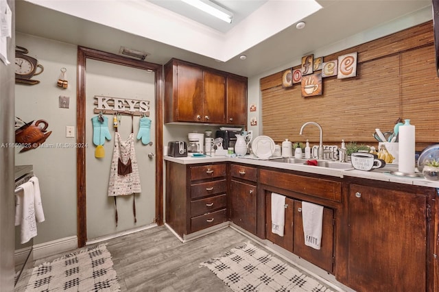 kitchen featuring range, sink, dark brown cabinetry, and light hardwood / wood-style floors