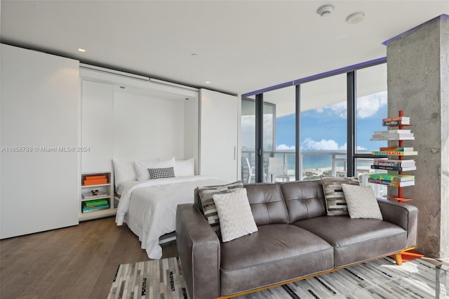 bedroom with hardwood / wood-style flooring, floor to ceiling windows, and a water view