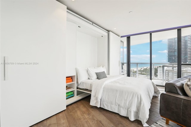 bedroom with floor to ceiling windows, dark hardwood / wood-style floors, and a water view