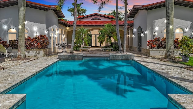 pool at dusk featuring a patio area