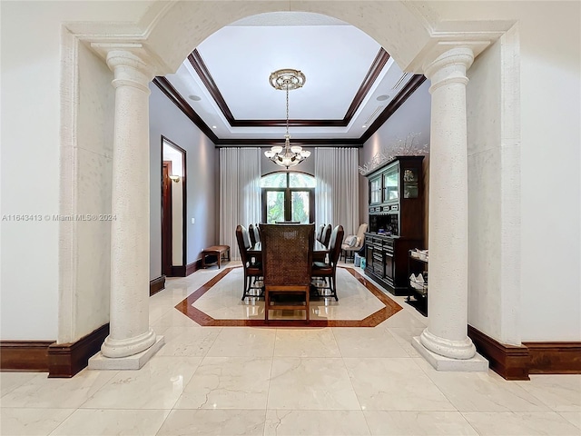 dining area featuring a chandelier, a raised ceiling, ornamental molding, and ornate columns