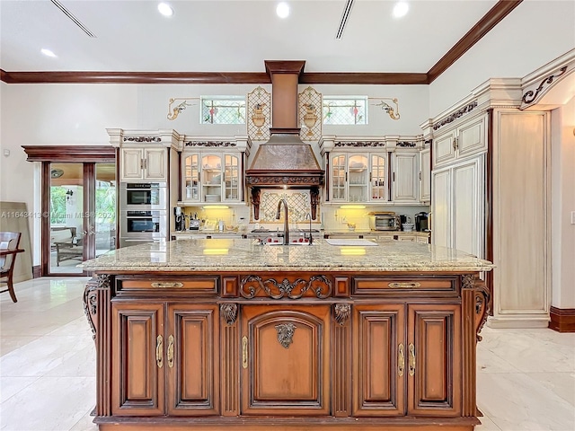 6710 SW 92nd St, Pinecrest, FL 33156 - kitchen with ornamental molding, a sink, a spacious island, glass insert cabinets, and light stone countertops