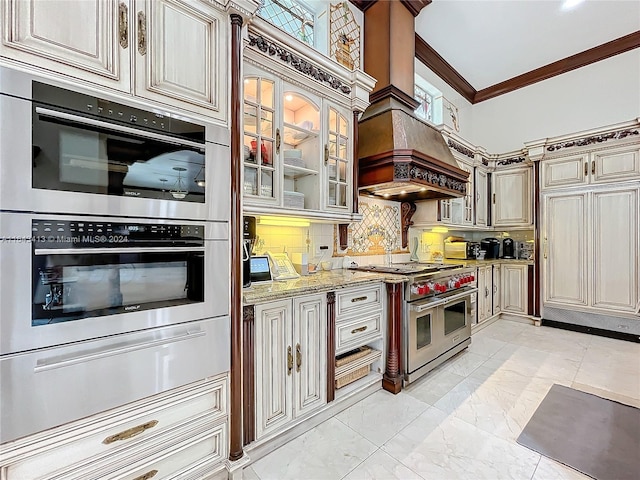 kitchen with light stone countertops, tasteful backsplash, crown molding, cream cabinets, and appliances with stainless steel finishes